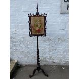 A Victorian rosewood pole screen with floral needlework panel in an elaborate frame, raised