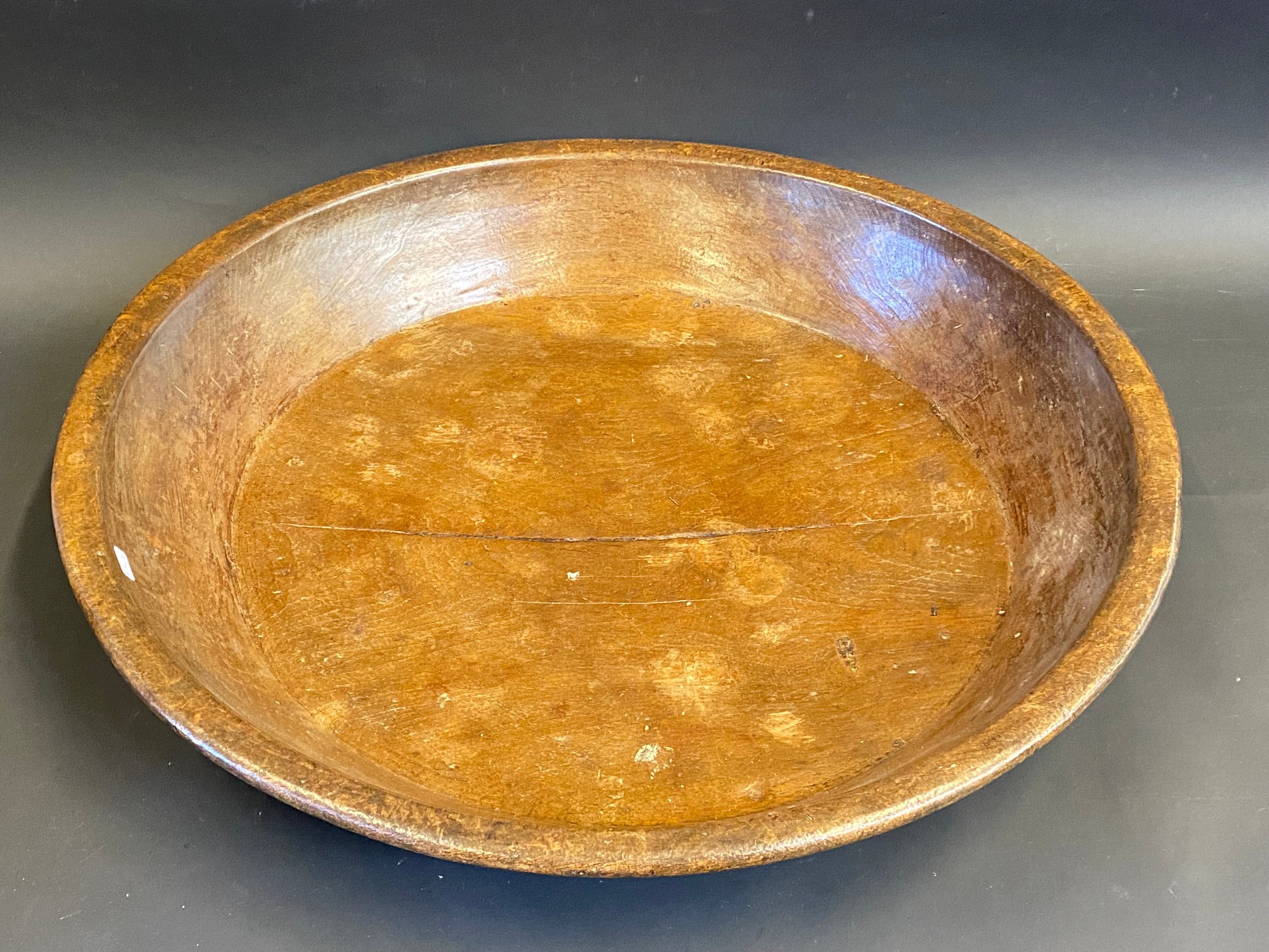 A large 19th Century wooden circular dish with raised rim, 21 1/2" diameter.