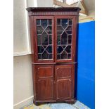 A mahogany floor standing corner cupboard with glazed doors above panelled doors on brack