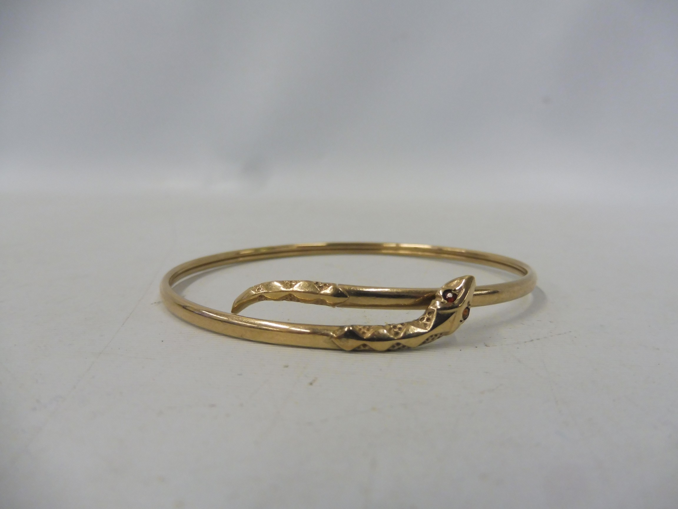 A 9ct gold snake bangle set with rubies, approx. 4.9g.