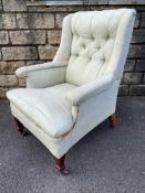 An Edwardian button back upholstered armchair, raised on square tapering supports, numbered and