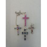 A multi-coloured sapphire cross on chain, a pink sapphire and diamond cross and two others.