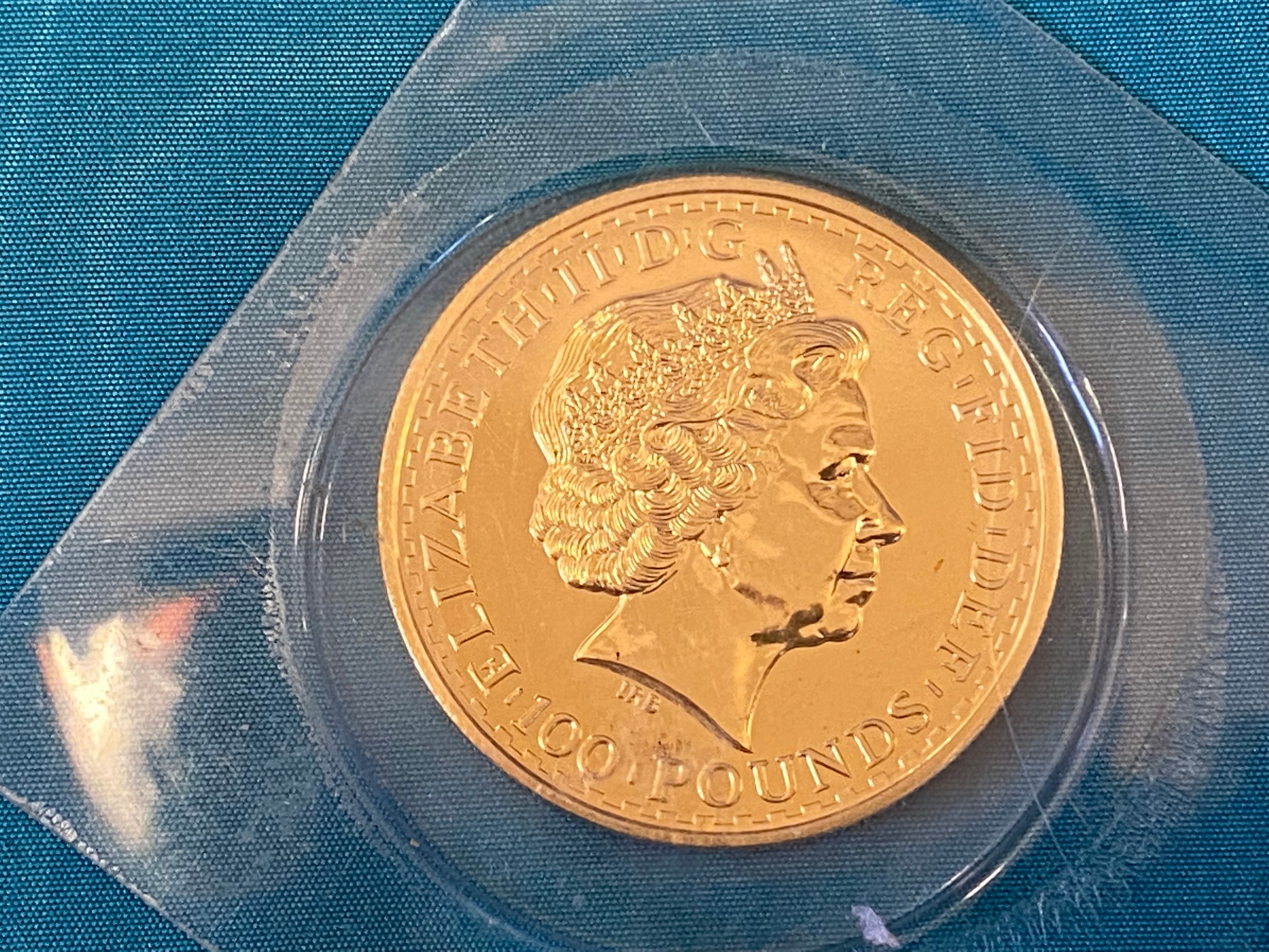 A rare gold 100 Pounds coin in plastic sleeve, overall weight approx. 35.7g.