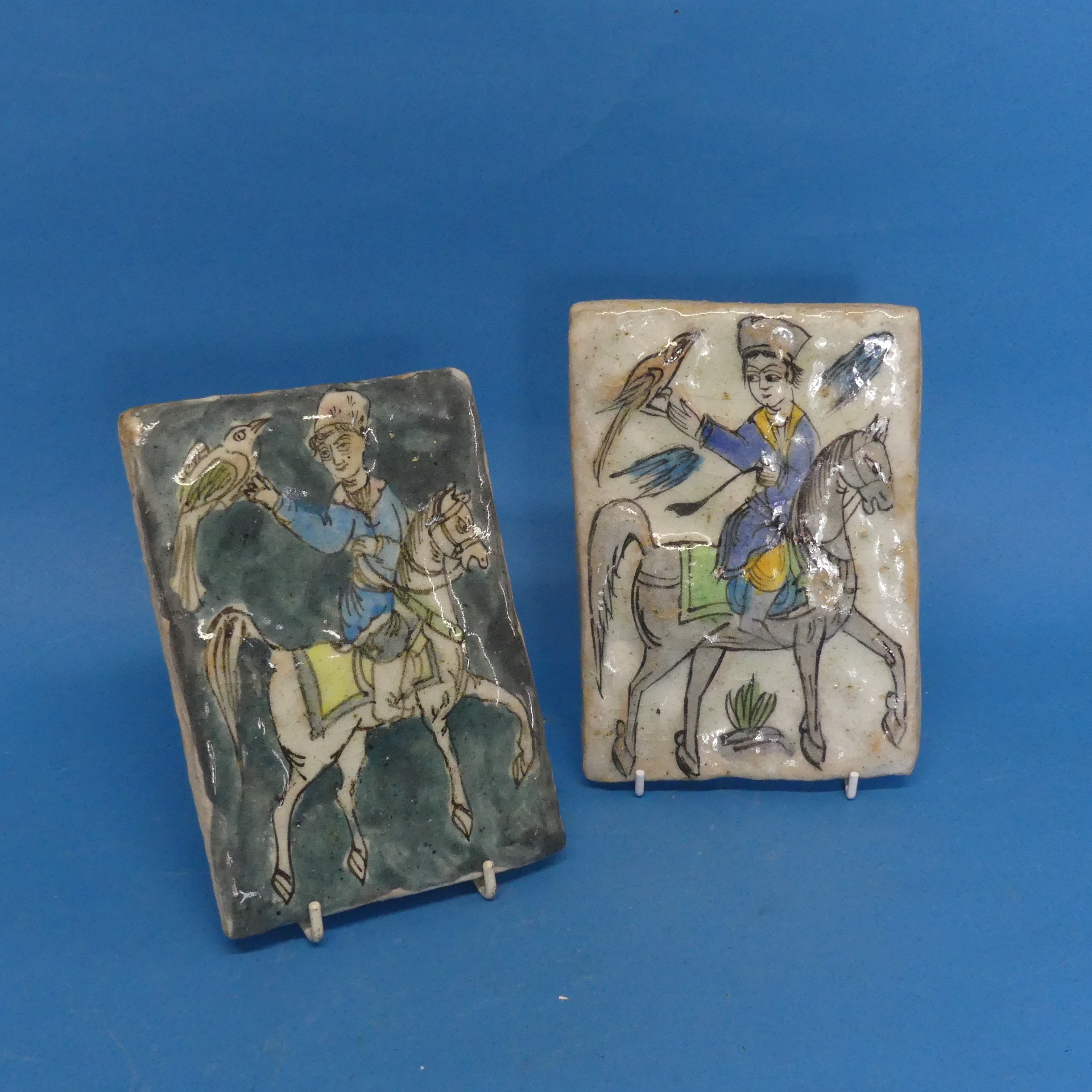 A pair of 19thC Persian Tiles, depicting a horse rider catching birds, somewhat in relief, 13cm x
