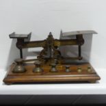 An antique set of brass Postal Scales, on wooden base, with complete set of six weights, the base