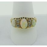A graduated three stone opal Ring, the oval opals each with two old cut diamonds set vertically