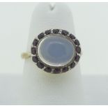 A moonstone and ruby Dress Ring, the central oval cabochon moonstone surrounded by sixteen small
