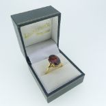 An 18ct yellow gold Dress Ring, the centre set with a large oval facetted red/deep orange stone,