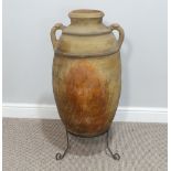 A large antique terracotta Urn, with twin handles, raised on wrought metal stand, H 84cm.