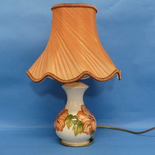 A Moorcroft 'Hibiscus' pattern Lamp, and shade, in cream ground with tube lined decoration, H25cm.