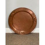 An Arts and Crafts copper Charger, the hammered centre with outer embossed scenes of a poacher and
