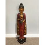 A Thai carved and gilt wood standing figure of a priest, holding a flower in one hand, on triangular