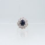 A sapphire and diamond cluster Ring, the oval facetted sapphire claw set above a surround of
