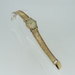 A 9ct gold lady's Omega Wristwatch, the champagne dial with baton markers, on 9ct gold mesh bracelet