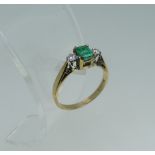An emerald and diamond three stone Ring, the central emerald cut emerald, c. 5mm x 3.6mm, with a