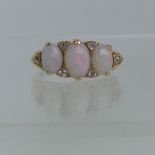 An early 20thC graduated three stone opal Ring, each with two diamond points set vertically  between