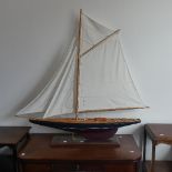 A vintage wooden Pond Yacht, the hull painted in red and blue, with canvas sails and metal fittings,