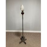 A wrought iron and red glass standard Lamp Stand with Oil Lamp, the red glass lamp with opaque glass