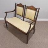An Edwardian mahogany framed two-seater Ladies Settee, the shaped top rail inlaid with classical
