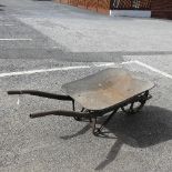 An antique rustic metal Wheelbarrow, with spoked wheel and two handles, rusted and weathered,