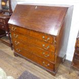 A George III oak Bureau, the fall front enclosing a inlaid fitted interior, raised on four