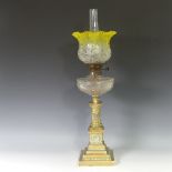 A brass squat column Oil Lamp, having a yellow etched frilled shade and clear glass font, raised