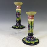 A pair of Moorcroft 'Violet' pattern Candlesticks, with tubelined decoration on green ground,