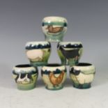 A set of six Moorcroft 'Farmyard' series Egg Cups, each with tube lined decoration on green