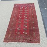 Tribal rugs; a red ground hand-knotted Afghan rug, 100 % wool, woven with two rows of ten Tekke, L