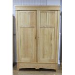 An antique pine double Wardrobe, with panel doors and shaped apron, W:125cm x H:205cm x D:63cm.