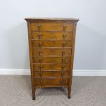 An Edwardian oak Arts & Crafts music cabinet, with eight fall-front drawers and brass handles, W: