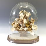 A Victorian stiffened fabric bouquet of flowers, arranged in a wicker basket, under glass dome on