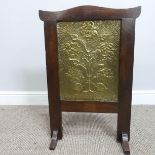 An Arts & Crafts embossed brass and oak Fire Screen, in the manner of John Pearson, decorated with