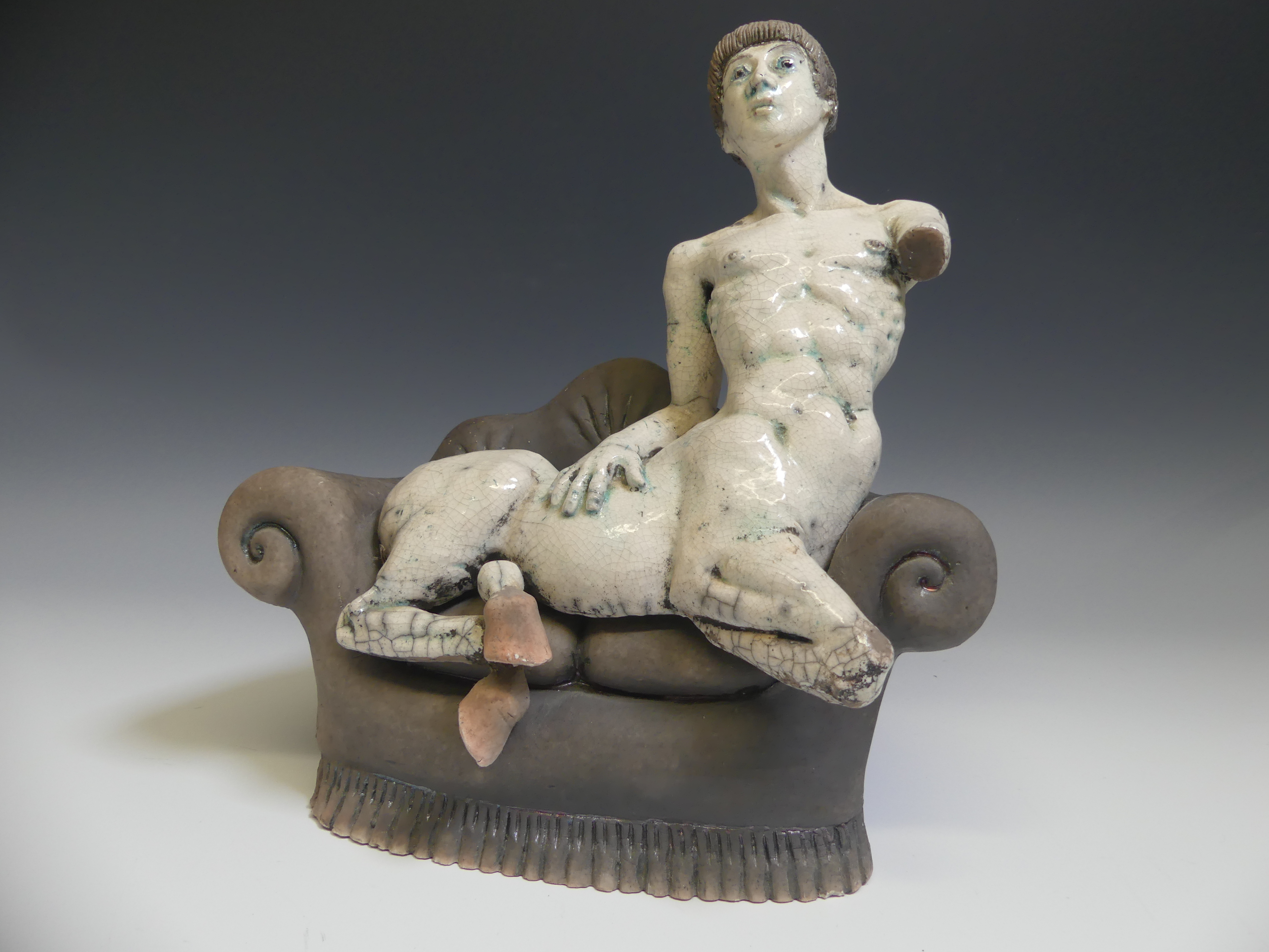 Lawson E. Rudge (b. 1936), a raku fired studio pottery sculpture of a Centaur on Sofa, H 31cm.