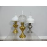 A brass and frosted glass Oil Lamp, the shade with motifs, together with two others similar, tallest