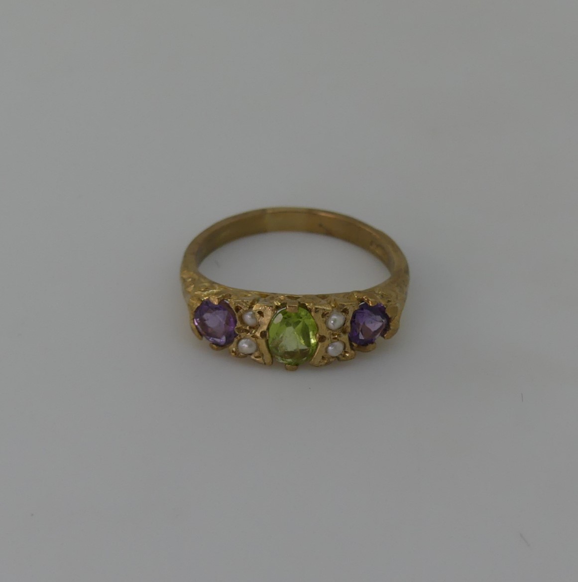 A Suffragette style three stone Ring, the central oval peridot with a circular amethyst on either