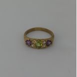 A Suffragette style three stone Ring, the central oval peridot with a circular amethyst on either