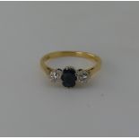 A sapphire and diamond three stone Ring, the central oval facetted sapphire 6.3mm long, with a