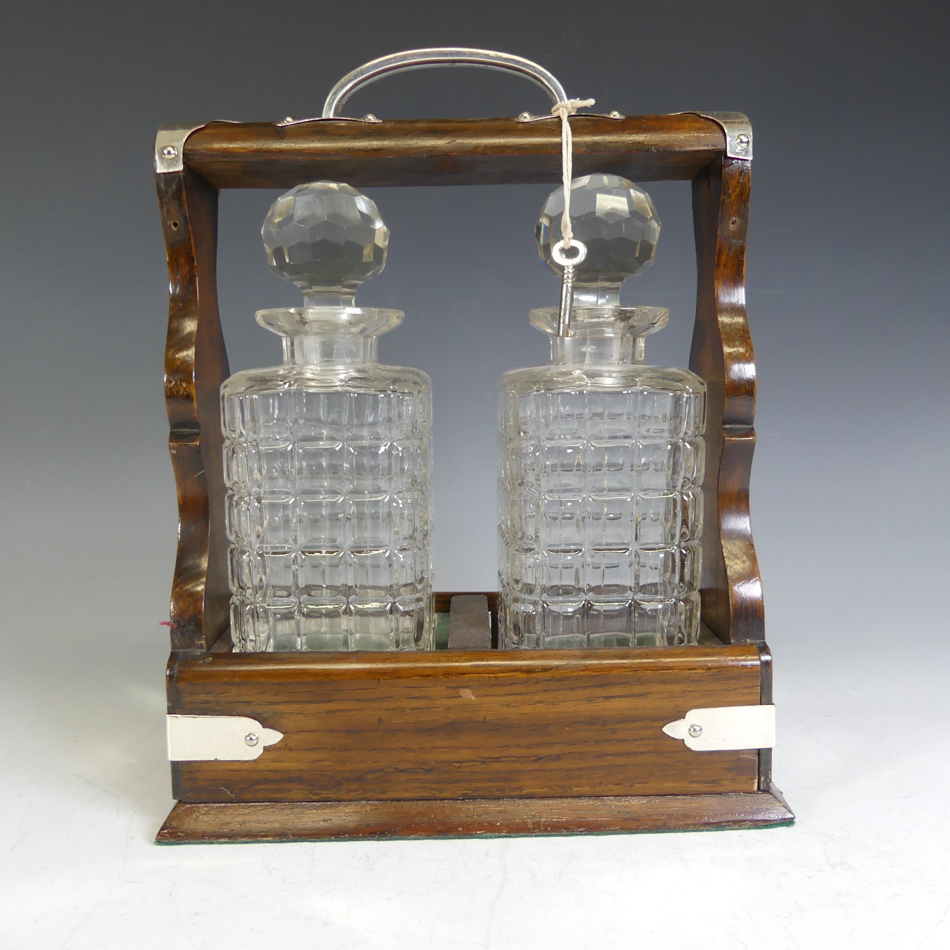 An Edwardian oak Tantalus, with silver-plated handle and mounts, encasing two cut glass decanters, - Image 2 of 4