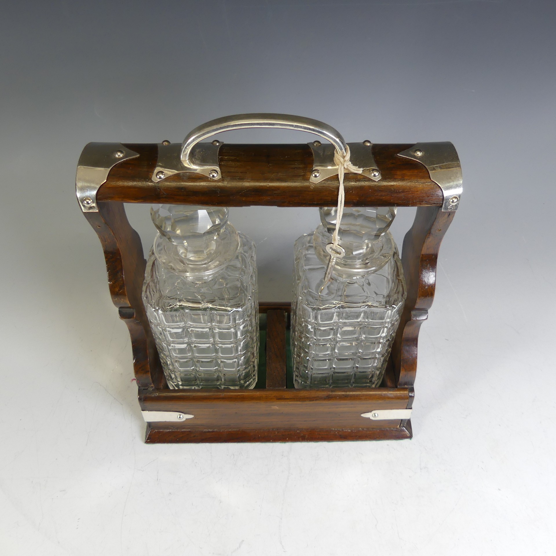 An Edwardian oak Tantalus, with silver-plated handle and mounts, encasing two cut glass decanters, - Image 3 of 4