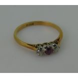 A small three stone ruby and diamond Ring, the circular pale ruby, approx 3mm diameter with a