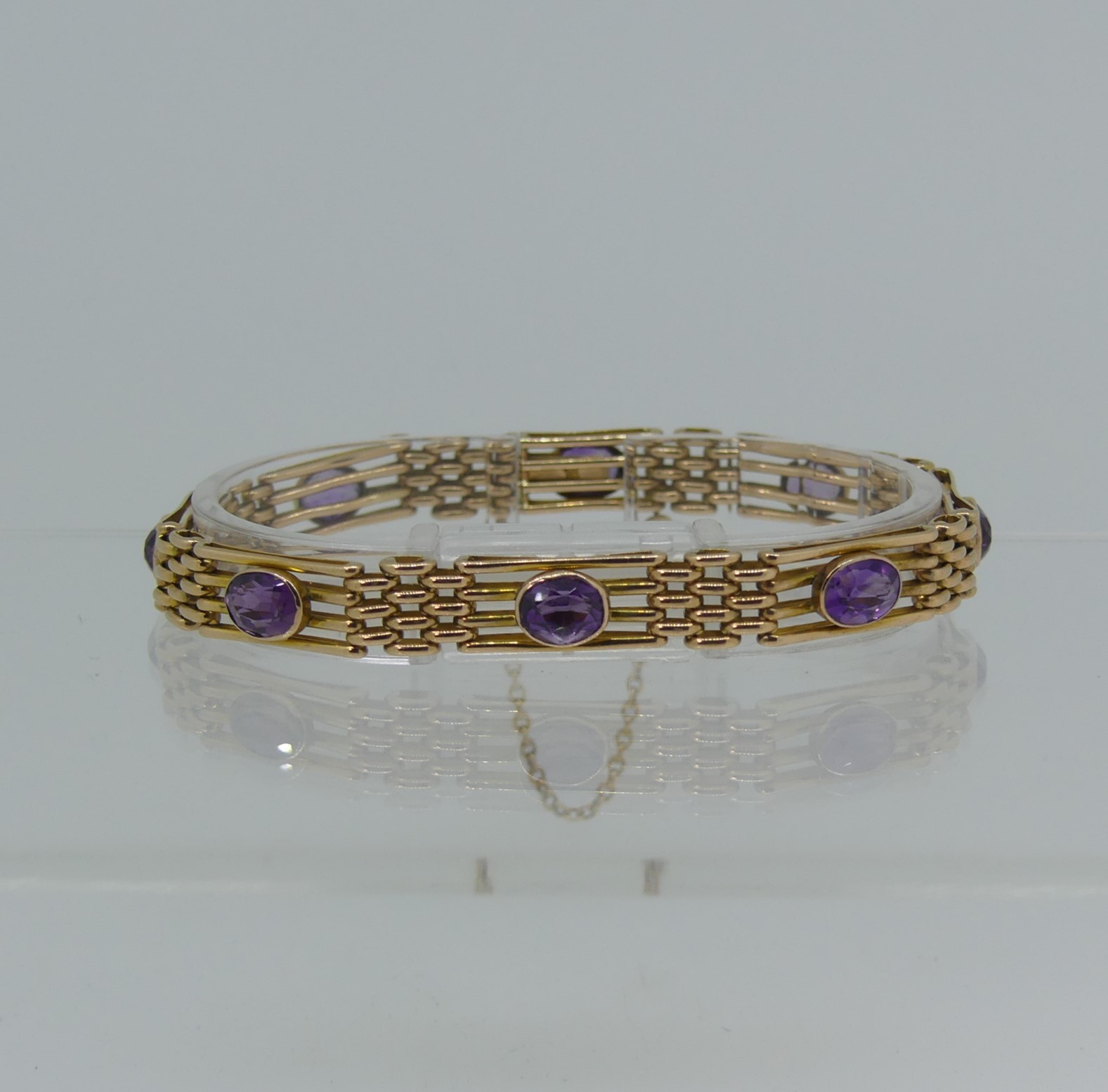 A 9ct yellow gold gatelink Bracelet, set with eight facetted amethysts, one link forming the