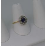 A sapphire and diamond cluster Ring, the circular facetted sapphire, 5.7mm diameter, claw set
