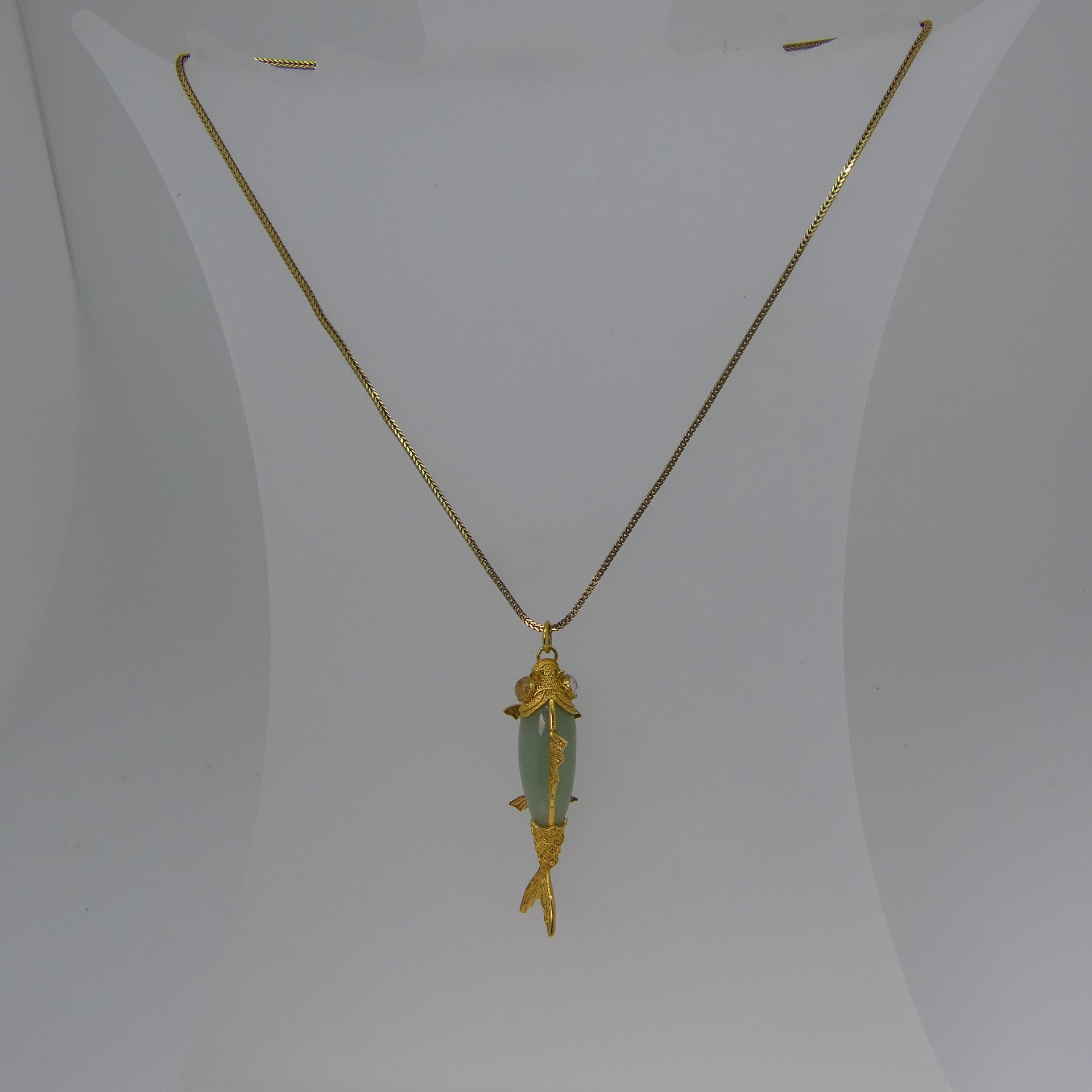 A 14ct filigree gold mounted jade Fish Pendant, with articulated tail, 4.7cm long, on a 9ct yellow