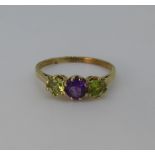 A peridot and amethyst three stone Ring, the central circular facetted amethyst, approx 4.6mm