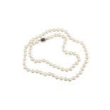 A cultured pearl necklace with a sapphire and diamond cluster clasp