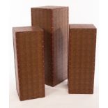 Three modern plinths in faux crocodile skin with studded borders, the largest 104cm high,