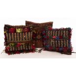 Three vintage Afghan saddlebag cushions with needlework decoration and fringed borders,