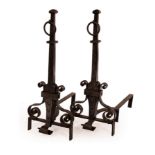A pair of wrought iron fire dogs with ring handles over scroll supports,