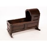 An oak cradle with an arch top hood and panelled sides, having a strung base,